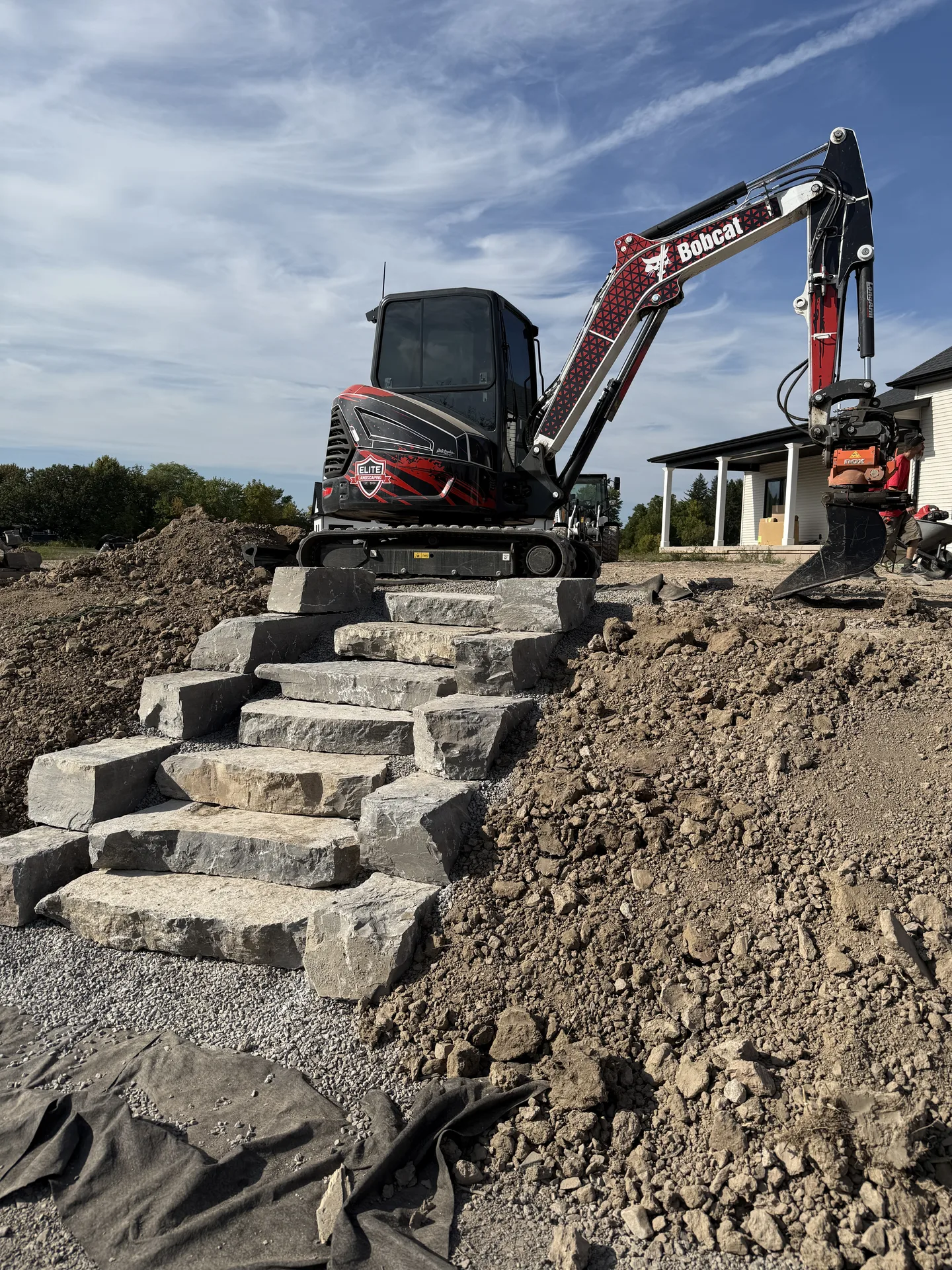 Excavator above a run of newly installed stone steps on a sloped project site